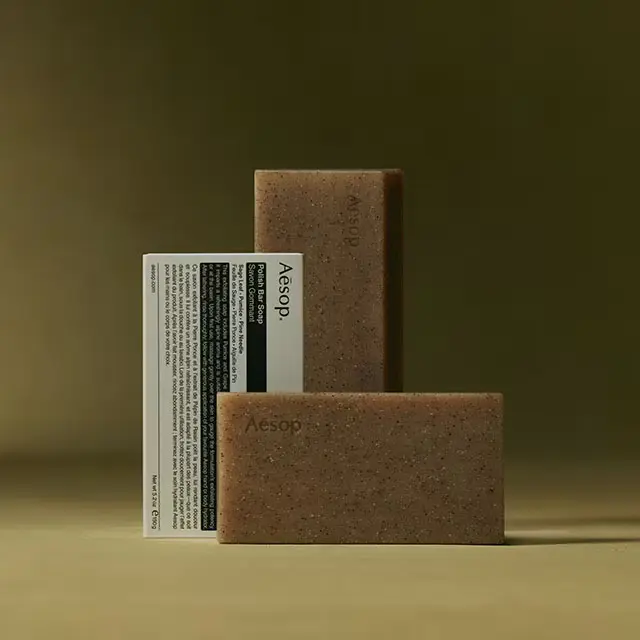 Aesop Polish Bar Soaps placed next to the packaging in dark yellow textured background