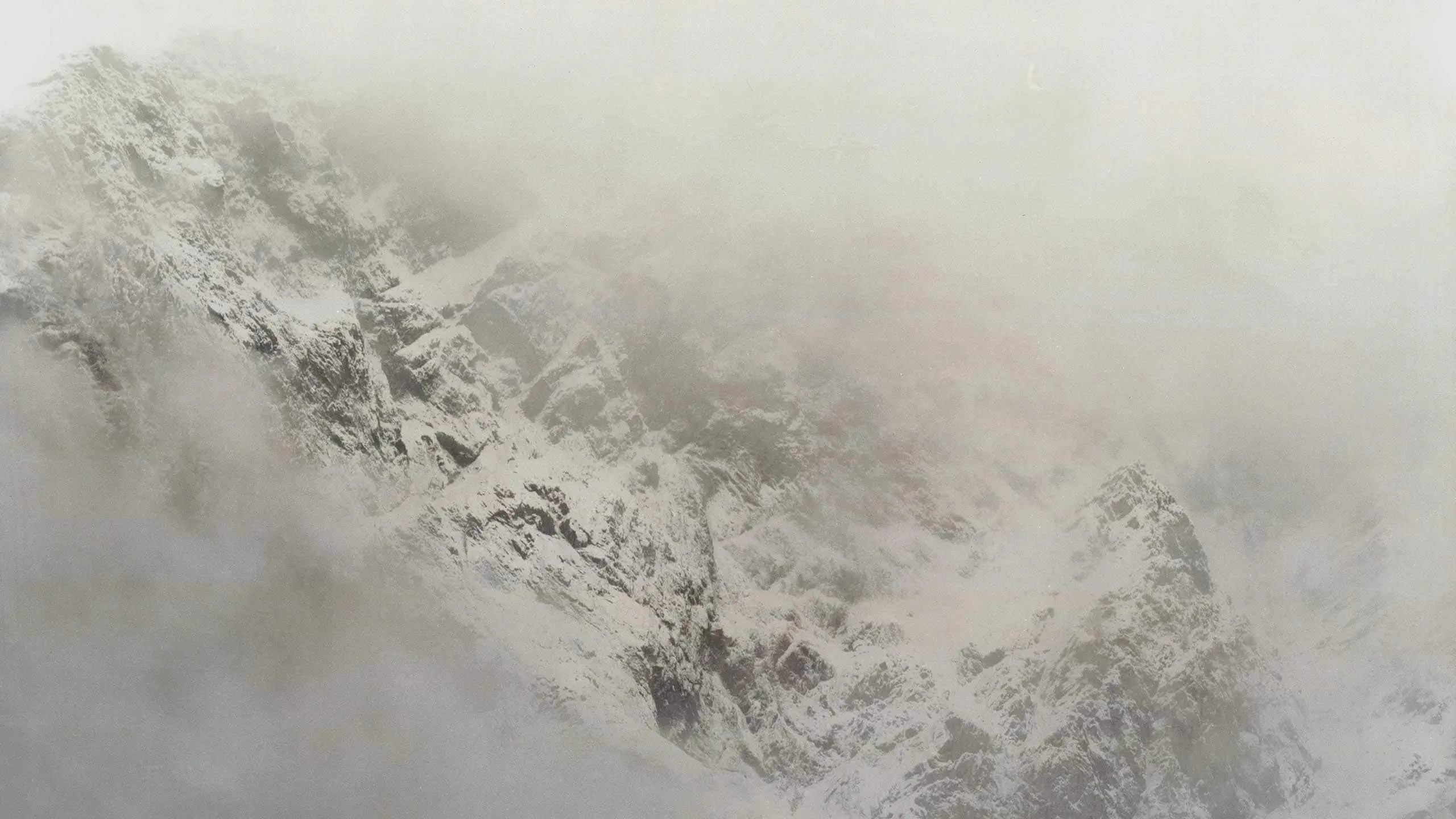 A winter snowy mountain surrounded by fog.