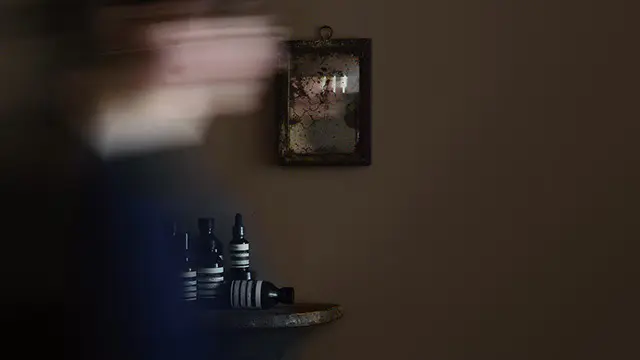 模糊的身影在老舊鏡子前移動，在背景中收集 Aesop 產品。